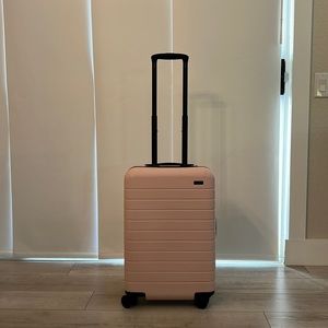 AWAY Bigger Carry On in Blush with charging port and laundry bag and dust cover.